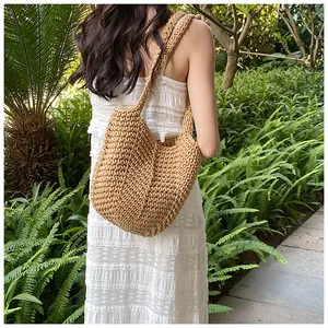 Detail of hand-woven bohemian bucket bag in light brown straw on a white lace dress