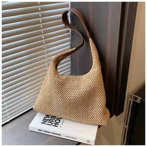 Dettaglio della borsa in paglia intrecciata a maglia larga con tracolla in pelle marrone