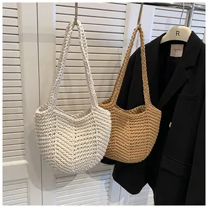 Detail of woven straw tote bags in cream and caramel brown hanging on a hanger
