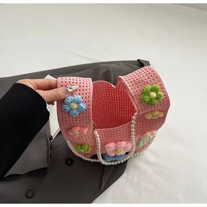 Detalle de bolso cubo de punto rosa con flores de ganchillo 3D y cadena de perlas