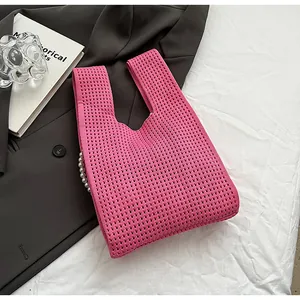 Detail der rosa Stricktasche mit Netzwebung und eleganter weißer Perlenkette am Trageriemen