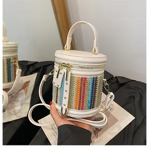 Detail of colorful woven bucket bag with white leather trim and gold zipper accents