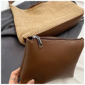 Dettaglio macro della borsa in paglia intrecciata e pochette in pelle per stile vacanza