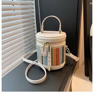 Detail of multi-color woven straw and white leather patchwork on a cylindrical bucket bag