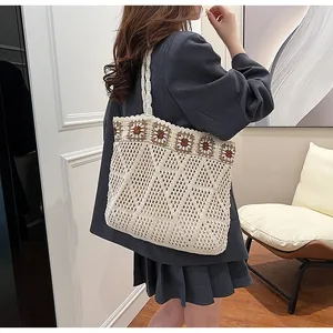 Close-up of knit tote bag featuring crochet flower details and hollow mesh texture