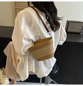 Close-up of beige woven bucket bag with leather strap and golden metal hooks