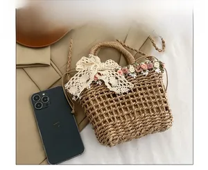 Detail of straw woven bucket bag with delicate white lace bow and floral accents