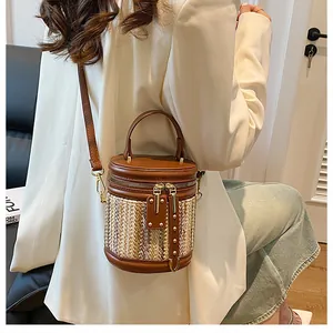 Detailed view of brown leather and woven bucket bag with gold rivets and zippers