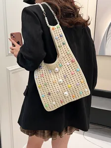 Elegante elfenbeinfarbene Häkeltasche mit bunten Perlen und Perlenriemen an Model