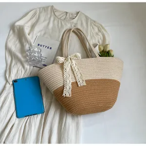 Detail of woven straw bag with white lace bow and dual-tone woven texture