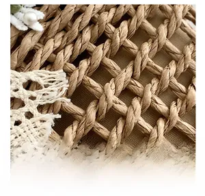 Detail showing handwoven brown straw texture with white lace trim and a pearl accent