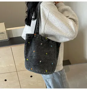 Détail de broderie de tulipes colorées sur un sac cabas en denim noir délavé pour le quotidien