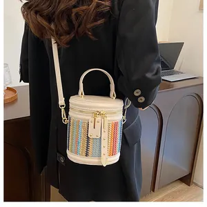 Detail view of the rainbow woven cylinder bucket bag with golden hardware and leather strap