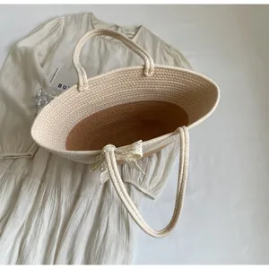 Detail of woven beach tote with lace bow and two-tone straw texture on beige dress