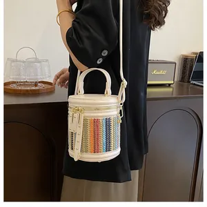 Detail of a chic rainbow woven bucket bag with cream leather trim and gold hardware