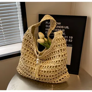 Détail du sac en paille bohème avec tissage ajouré et pompon orné de perles