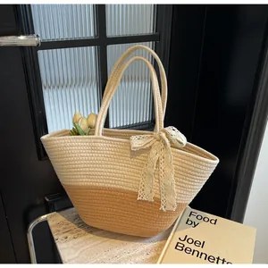 Detail view of woven tote with contrast paneling and delicate beige lace bow