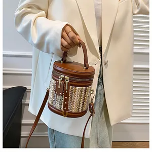 Detailed view of woven bucket bag with brown leather trim and golden zipper closure