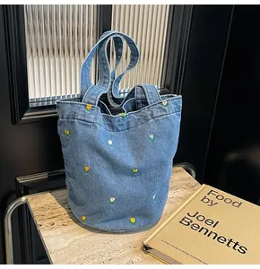 Détail de la broderie florale sur le sac en jean bleu sur une surface en marbre