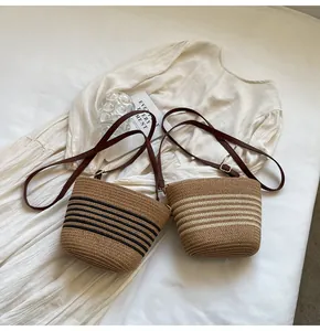 Detail of woven straw bucket bags with leather straps and nautical stripes on a white dress