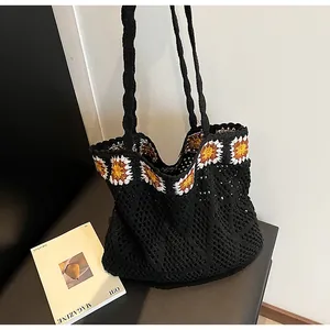 Detailed close-up of a black crochet tote bag with sunflower knit pattern and dual straps