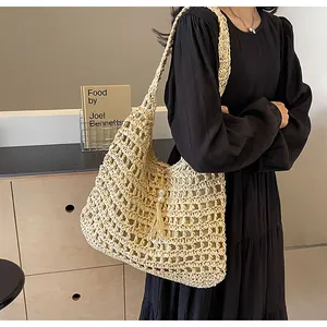 Détail d'un sac bandoulière en paille avec texture crochetée et pompons décoratifs en perles