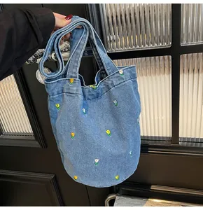 Détail de la broderie florale sur un sac cabas en denim bleu clair avec bandoulière