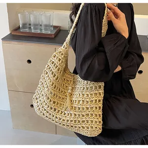 Détail d'un sac bandoulière en paille avec pompon en perles sur un modèle en robe noire