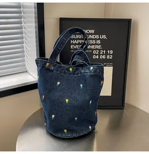 Gros plan détaillé sur la broderie de tulipes colorées sur un sac seau en jean foncé