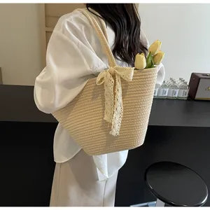 Detail of hand-woven straw tote with elegant beige lace bow and natural texture finish