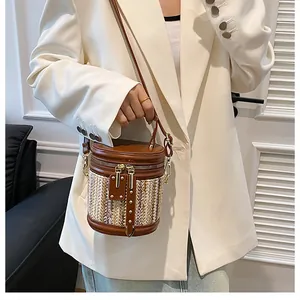 Detail of a chic woven bucket bag with smooth leather trim and dual metal zippers