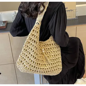 Détail d'un sac bandoulière en paille avec tricot ajouré fin et pompon en perles