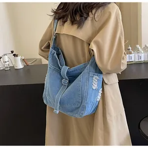 Detail der blauen Denim-Tasche mit Distressed-Kanten und verstellbarer Metallschnalle