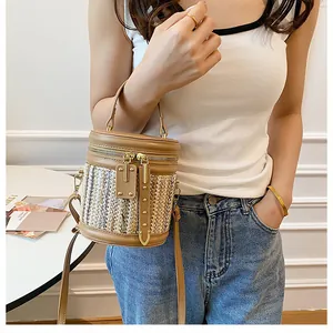 Close-up of rainbow woven bucket bag featuring brown leather trim and gold metal zippers