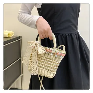 Detail of woven straw handbag with floral lace bow decoration and braided handles