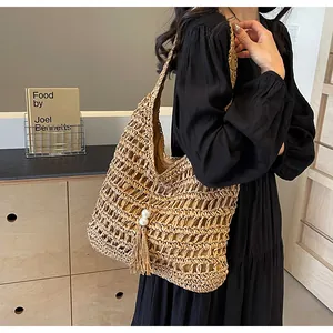 Détail d'un sac en paille bohème avec tissage ajouré et breloques à pompons perle