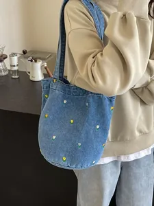 Sac seau en jean avec broderie tulipe présenté de profil porté par un mannequin