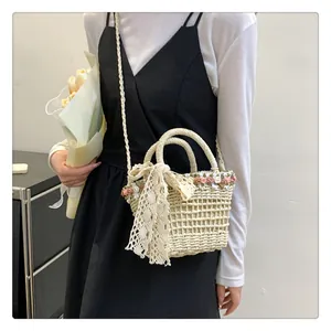 Detail of hand-woven straw bucket bag with floral accents and a lace bow charm
