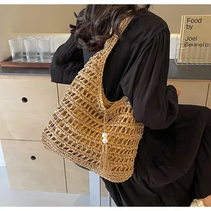Détail d'un sac bandoulière en paille bohème avec de grandes perles et de longs glands