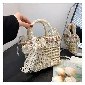 Detail of straw woven bucket bag with ribbon flowers and lace bow on wooden table