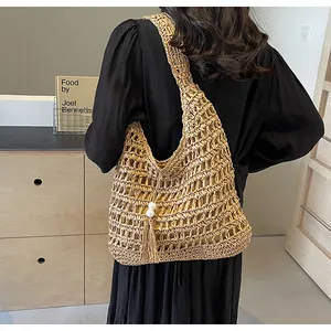 Détail du sac hobo bohème en paille tressée avec pompon en perles sur un mannequin