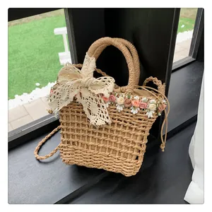 Detail of straw bucket bag with lace bow and floral accents on a nature background