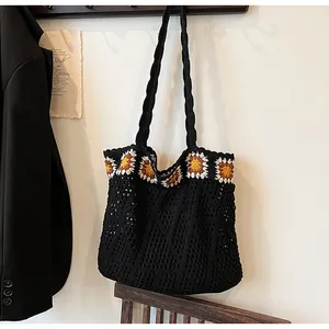 Detailed knit texture of a black crochet tote bag featuring vibrant sunflower patterns
