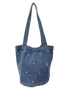 Sac seau en jean bleu avec broderies florales et longues bandoulières sur fond blanc