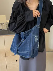 Dunkelblaue Denim-Umhängetasche mit Kontrastnähten und dekorativen Fransentaschen