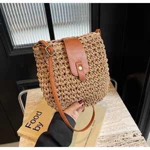 Détail du sac bandoulière en paille tressée avec lanière en cuir brun et boucle métal