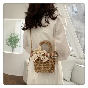 Detail of straw woven bucket bag with lace bow and floral accents on a model