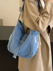 Klassische blaue Denim Hobo Tasche mit Fransen und verstellbarem Gurt am Modell