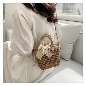 Detail of hand-woven straw bucket bag with white lace bow and small floral accents
