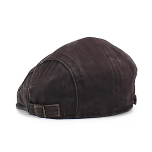 Detail view of adjustable metal buckle on a retro washed cotton flat cap in dark brown